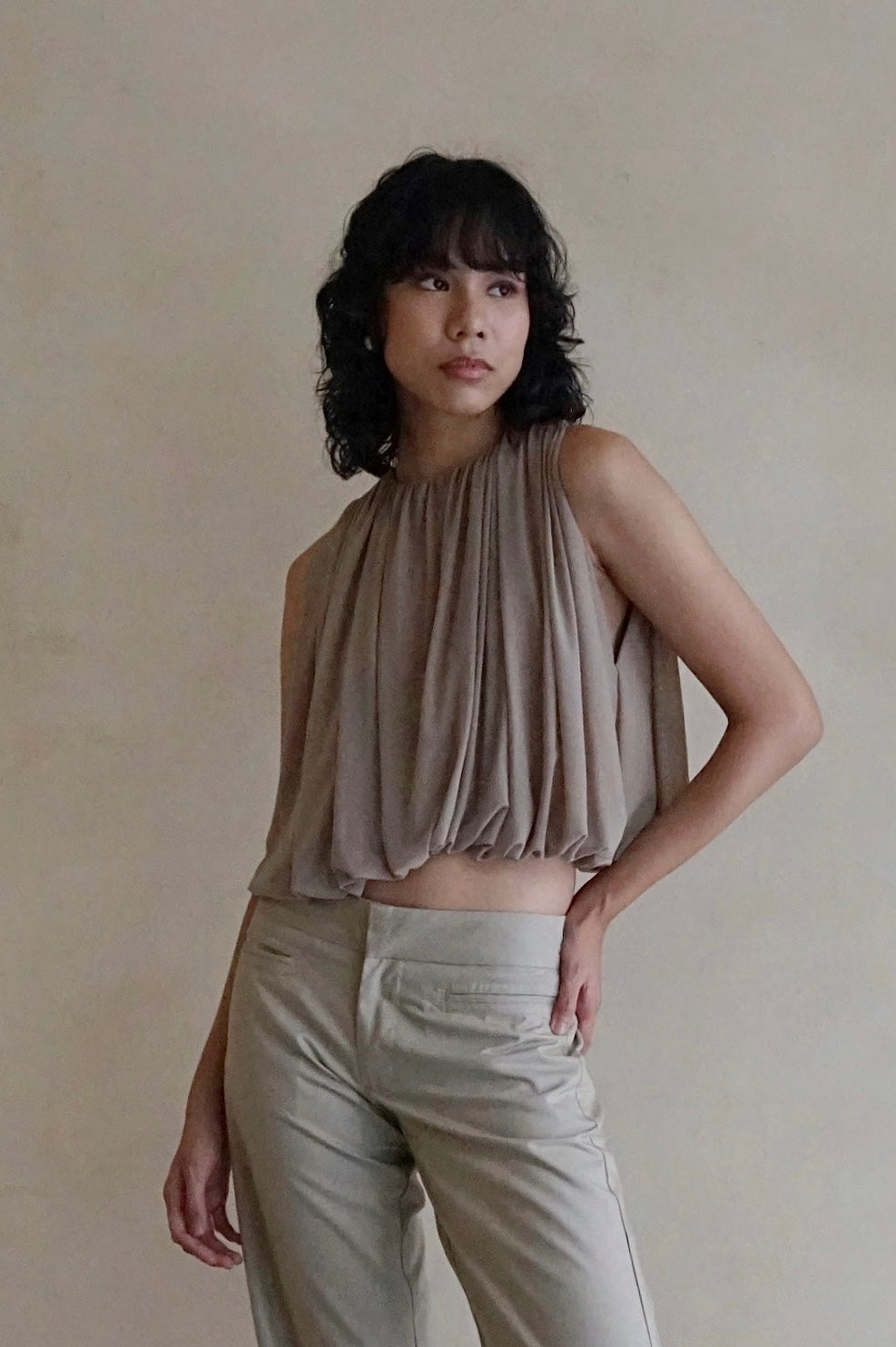 Woman wearing a beige top and light-colored pants against a plain background
